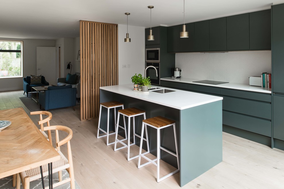 Photo of a modern single-wall eat-in kitchen in London with a drop-in sink, flat-panel cabinets, grey cabinets, quartzite benchtops, light hardwood floors, with island and white benchtop.