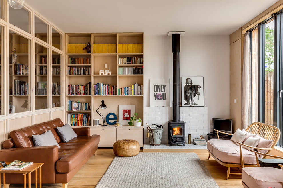 This is an example of a mid-sized midcentury living room in Buckinghamshire with beige walls, a wood stove, a brick fireplace surround, a freestanding tv, brown floor and medium hardwood floors.