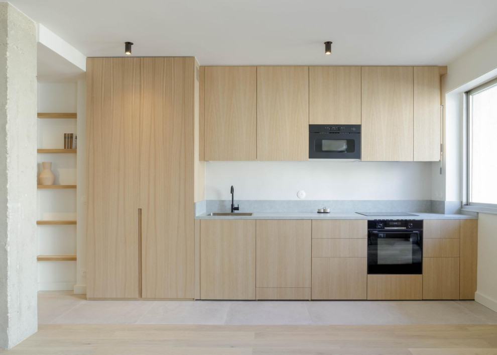 Idée de décoration pour une cuisine ouverte linéaire, encastrable et blanche et bois design en bois clair de taille moyenne avec un évier encastré, un placard à porte affleurante, un plan de travail en surface solide, une crédence grise, une crédence en carreau de ciment, parquet clair, aucun îlot, un sol beige et un plan de travail blanc.
