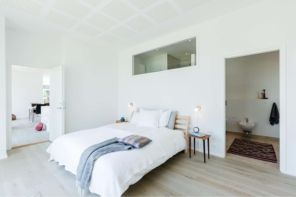 This is an example of a mid-sized scandinavian master bedroom in Aarhus with white walls, light hardwood floors and no fireplace.