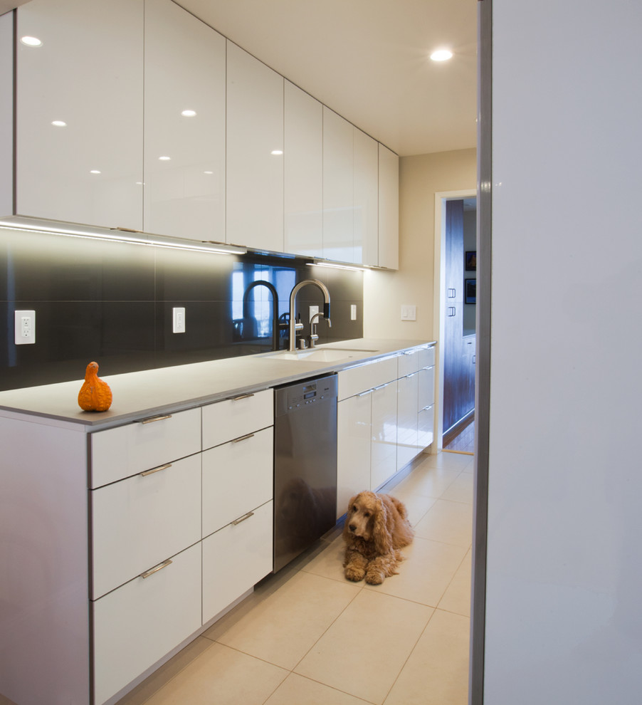 This is an example of a mid-sized contemporary galley eat-in kitchen in San Francisco with an undermount sink, flat-panel cabinets, white cabinets, quartz benchtops, black splashback, glass tile splashback, stainless steel appliances and no island.