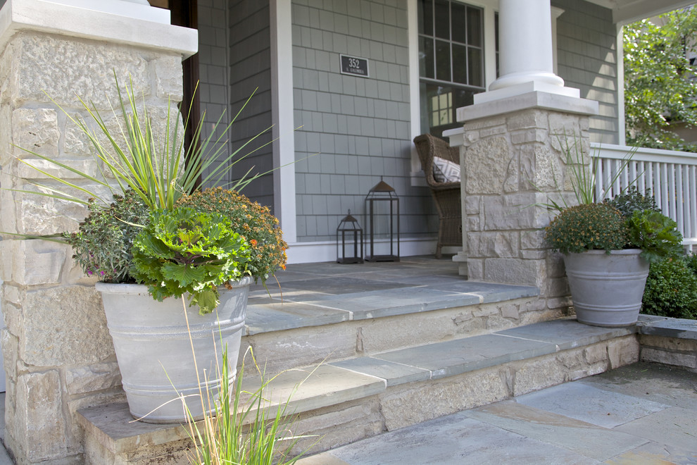 Photo of a large beach style front yard verandah in Chicago with natural stone pavers and a roof extension.