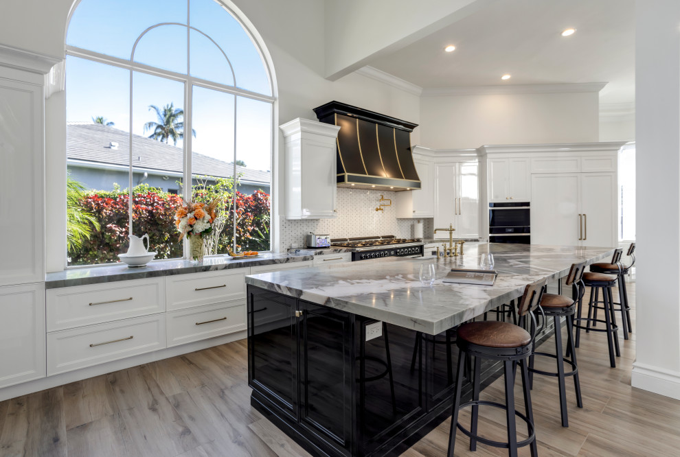 Large transitional galley dark wood floor and brown floor kitchen photo in Miami with a farmhouse sink, recessed-panel cabinets, white cabinets, quartzite countertops, multicolored backsplash, mosaic tile backsplash, black appliances, an island and multicolored countertops