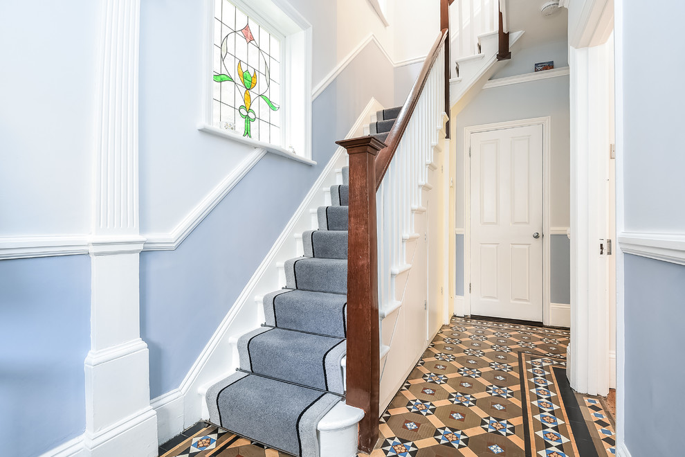 This is an example of a traditional carpeted l-shaped staircase in London with carpet risers and wood railing.