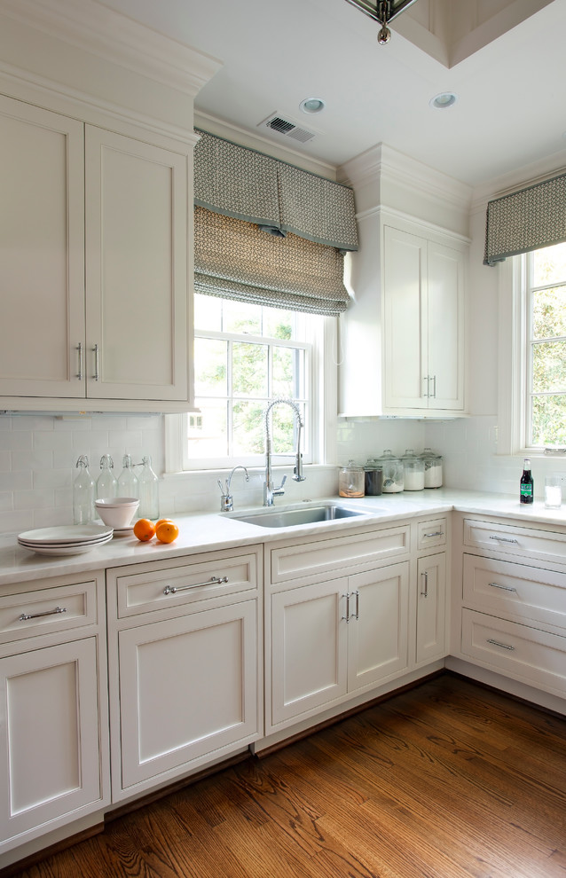 Photo of a traditional kitchen in Charlotte with shaker cabinets, white cabinets, white splashback and subway tile splashback.