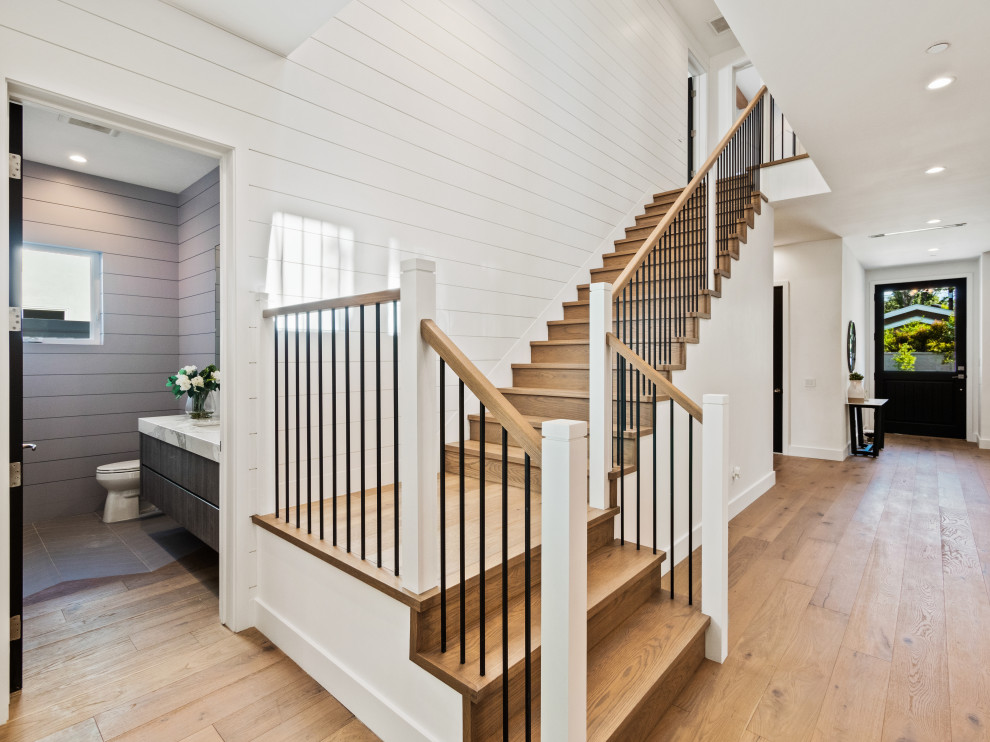Large country wood l-shaped staircase in Los Angeles with wood risers, wood railing and panelled walls.