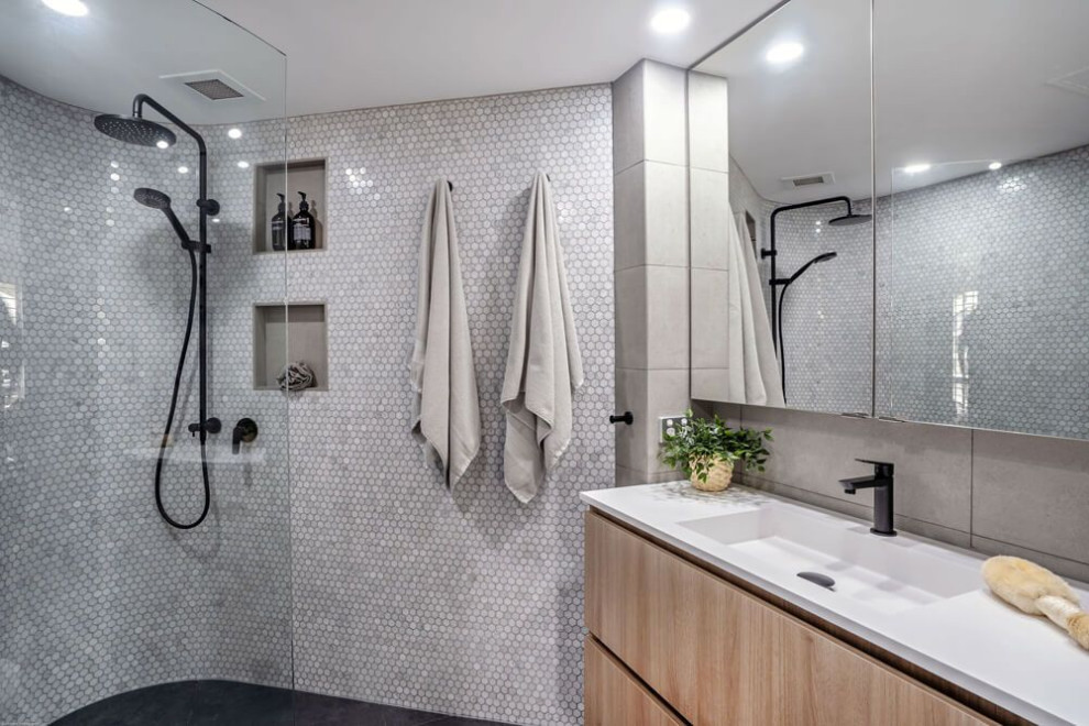 Photo of a mid-sized contemporary 3/4 bathroom in Gold Coast - Tweed with flat-panel cabinets, light wood cabinets, a corner shower, gray tile, porcelain tile, an integrated sink, black floor, white benchtops, a niche, a single vanity and a built-in vanity.