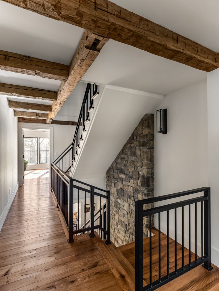 Diseño de escalera en U campestre grande con escalones de madera, contrahuellas de madera pintada y barandilla de metal