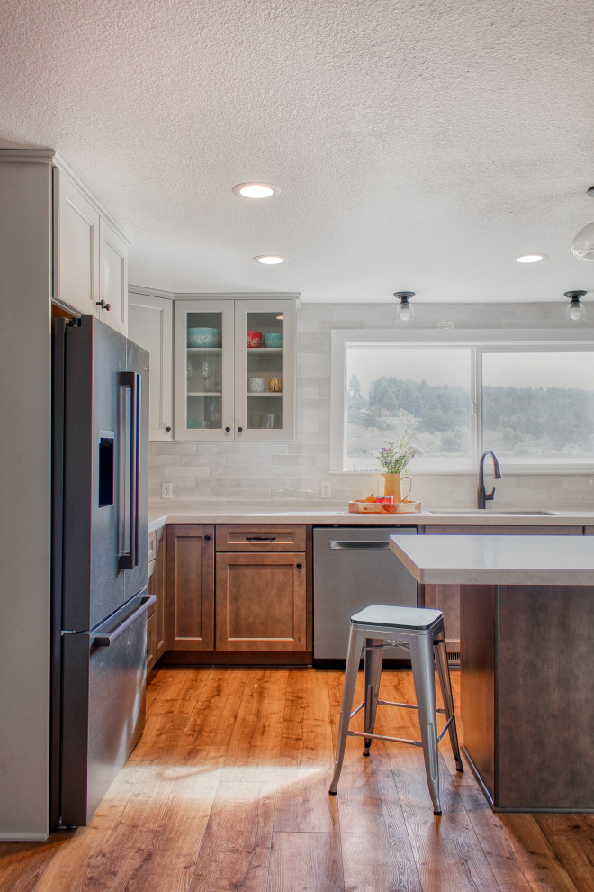 Inspiration for a mid-sized transitional u-shaped light wood floor and brown floor eat-in kitchen remodel with an undermount sink, recessed-panel cabinets, medium tone wood cabinets, solid surface countertops, white backsplash, ceramic backsplash, stainless steel appliances, an island and white countertops
