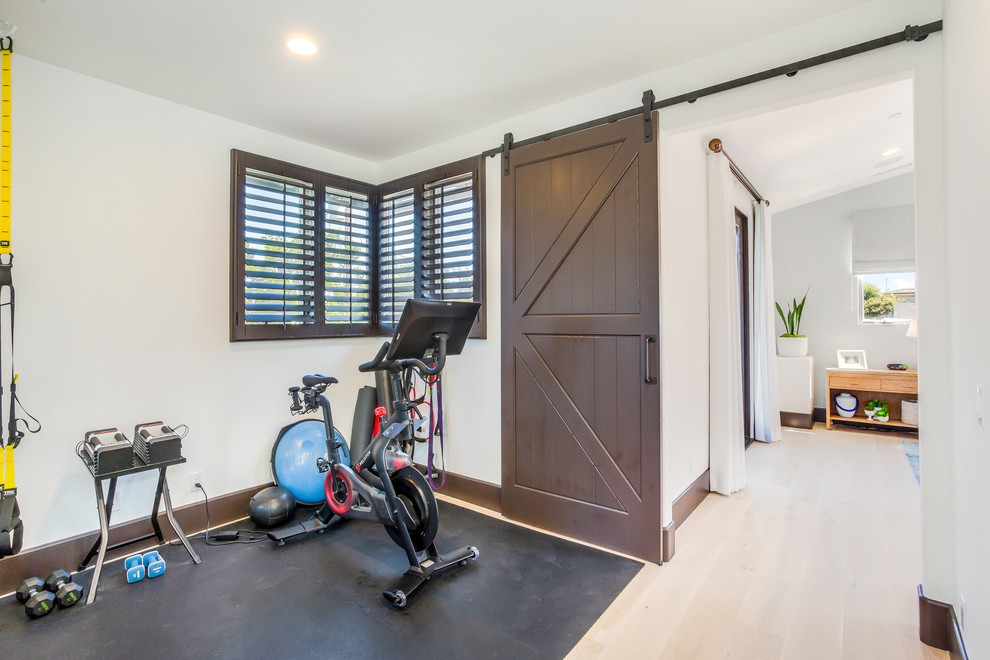 This is an example of a small mediterranean multipurpose gym in Orange County with white walls, light hardwood floors and beige floor.