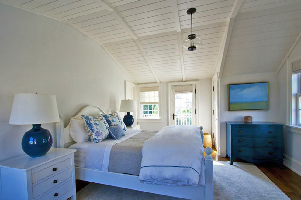 Ejemplo de habitación de invitados abovedada costera grande sin chimenea con paredes blancas, suelo de madera en tonos medios y suelo marrón