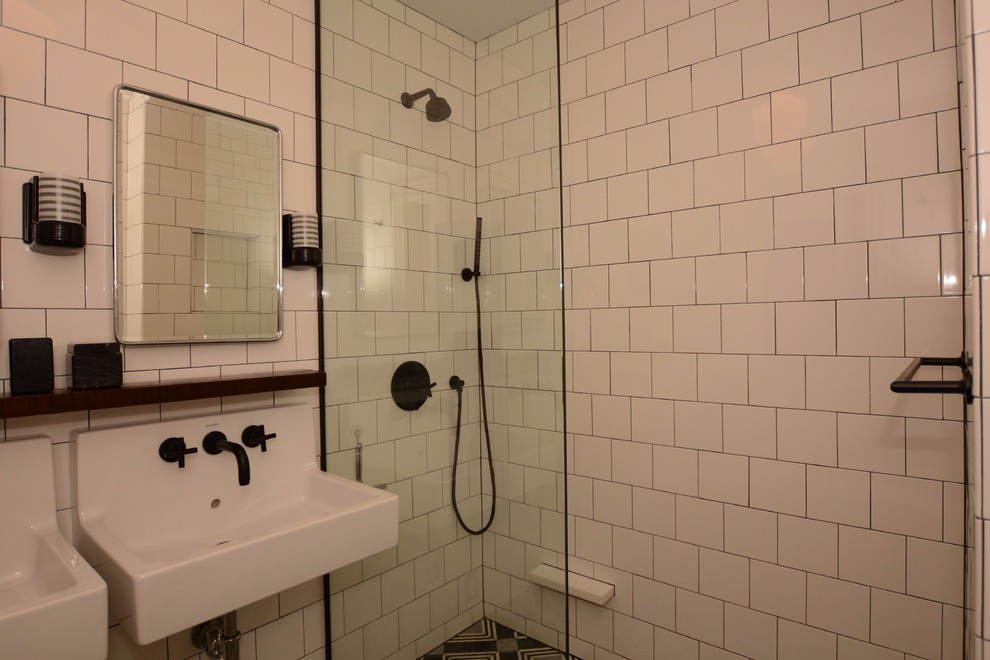 Inspiration for a small contemporary 3/4 bathroom in New York with open cabinets, black cabinets, a curbless shower, a two-piece toilet, white tile, porcelain tile, white walls, cement tiles, a wall-mount sink, solid surface benchtops, black floor and a hinged shower door.