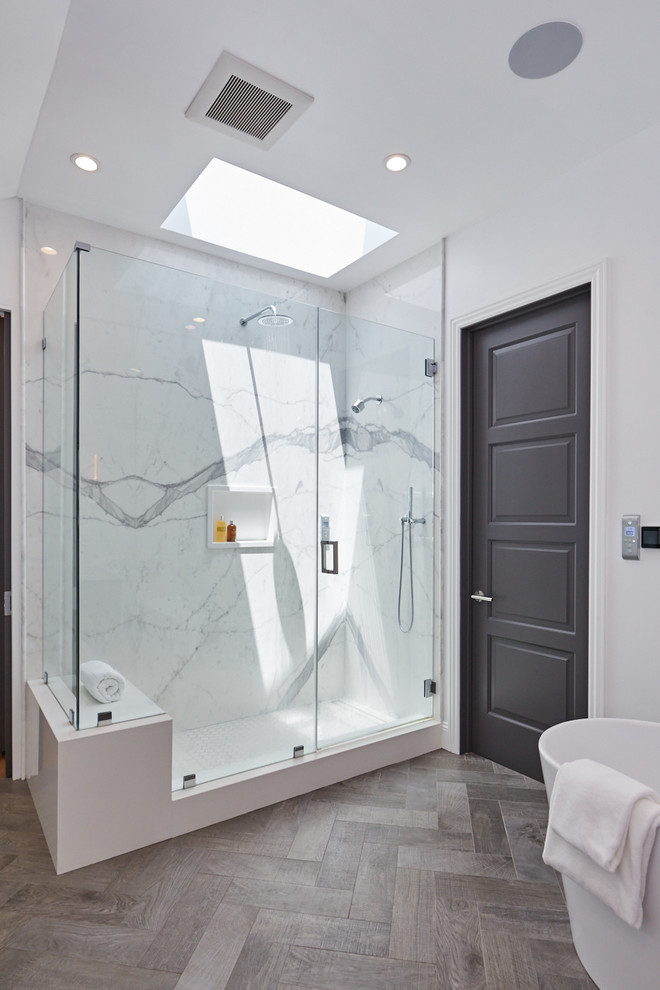 Mid-sized transitional master bathroom in Los Angeles with raised-panel cabinets, grey cabinets, a freestanding tub, a corner shower, a wall-mount toilet, white tile, porcelain tile, white walls, porcelain floors, an undermount sink, marble benchtops, grey floor and a hinged shower door.