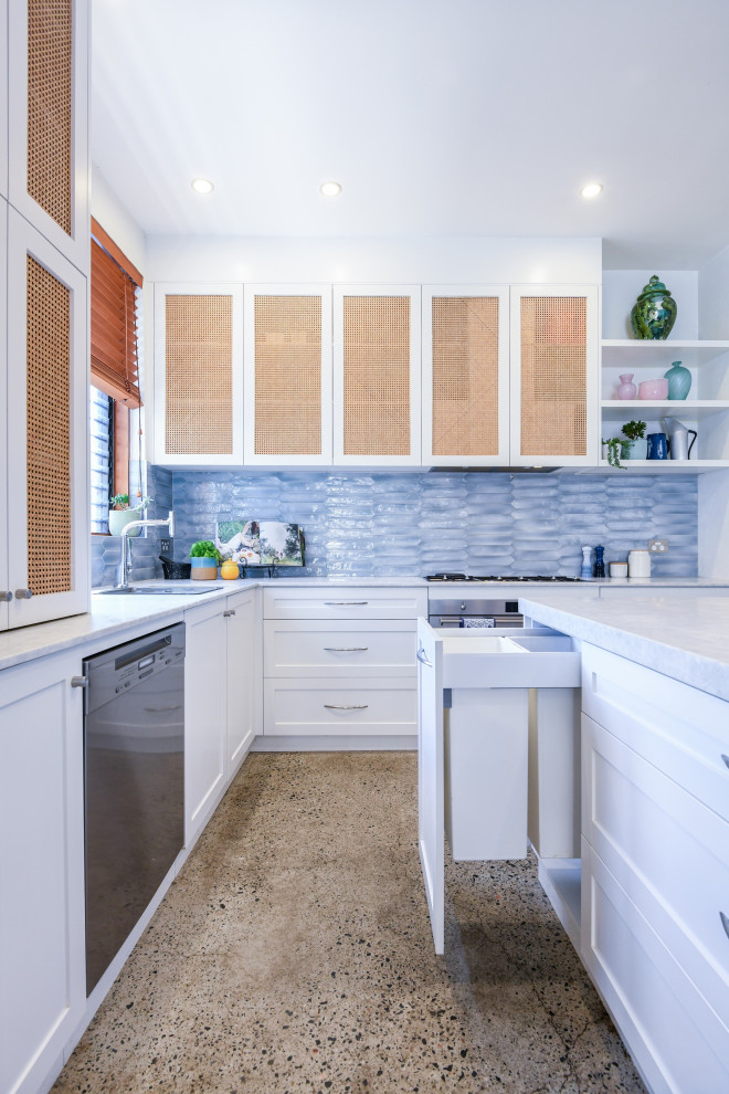 Large beach style l-shaped open plan kitchen in Sydney with an undermount sink, shaker cabinets, white cabinets, quartzite benchtops, blue splashback, ceramic splashback, stainless steel appliances, concrete floors, with island, grey floor and grey benchtop.