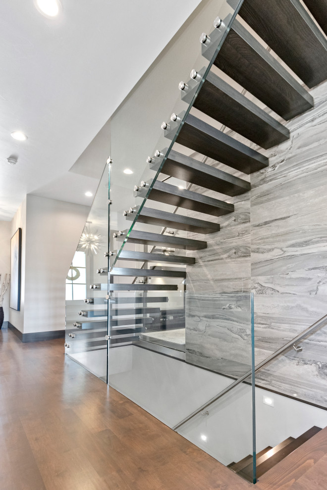 Contemporary wood floating staircase in Other with open risers and glass railing.