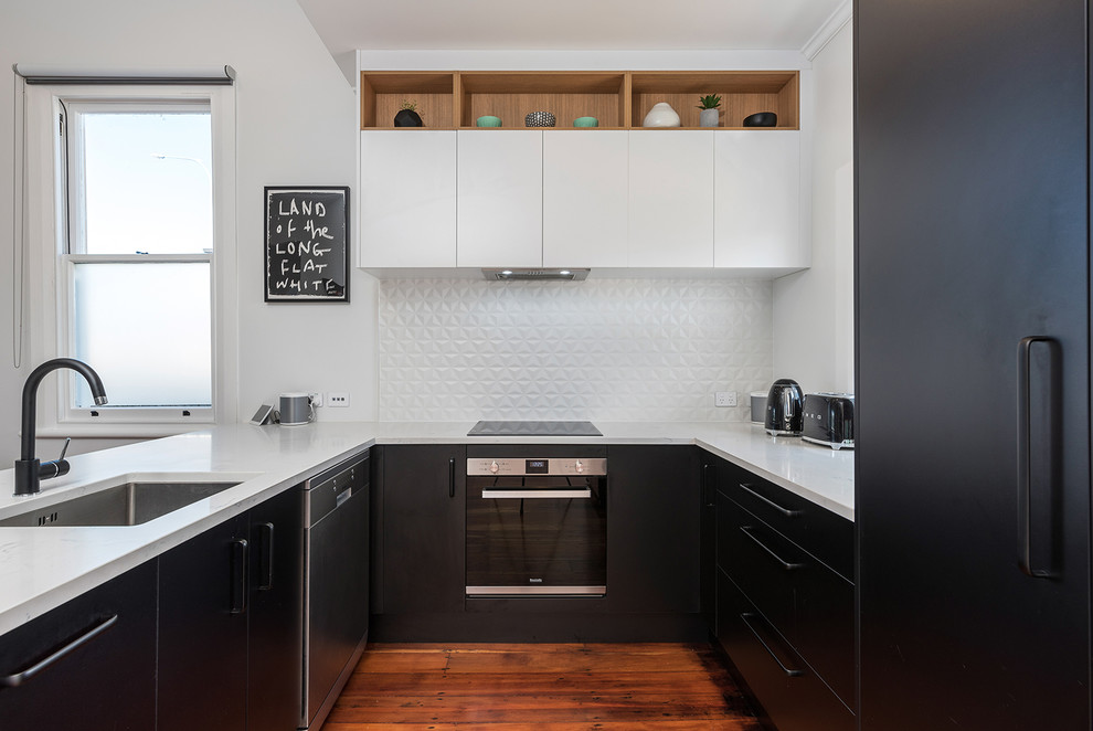 Design ideas for a mid-sized modern u-shaped eat-in kitchen in Auckland with an undermount sink, flat-panel cabinets, black cabinets, laminate benchtops, white splashback, ceramic splashback, stainless steel appliances, medium hardwood floors and brown floor.