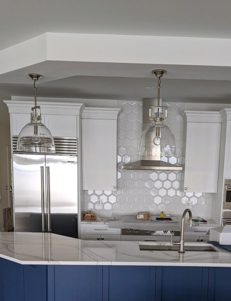 Example of a mid-sized transitional kitchen design in Other with an undermount sink, recessed-panel cabinets, white cabinets, quartz countertops, white backsplash, ceramic backsplash, stainless steel appliances, an island and white countertops