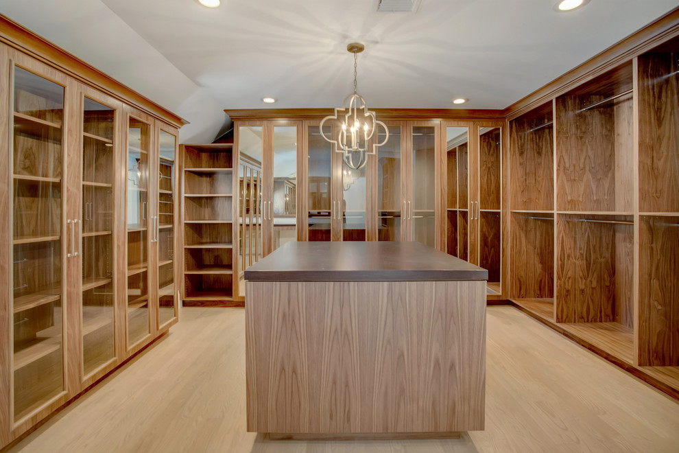 Design ideas for an expansive transitional gender-neutral walk-in wardrobe in New York with light hardwood floors, brown floor, glass-front cabinets and medium wood cabinets.