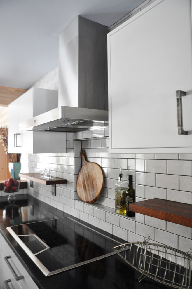 Eat-in kitchen - mid-sized transitional l-shaped dark wood floor eat-in kitchen idea in Grand Rapids with an undermount sink, flat-panel cabinets, white cabinets, soapstone countertops, white backsplash, subway tile backsplash, stainless steel appliances and an island