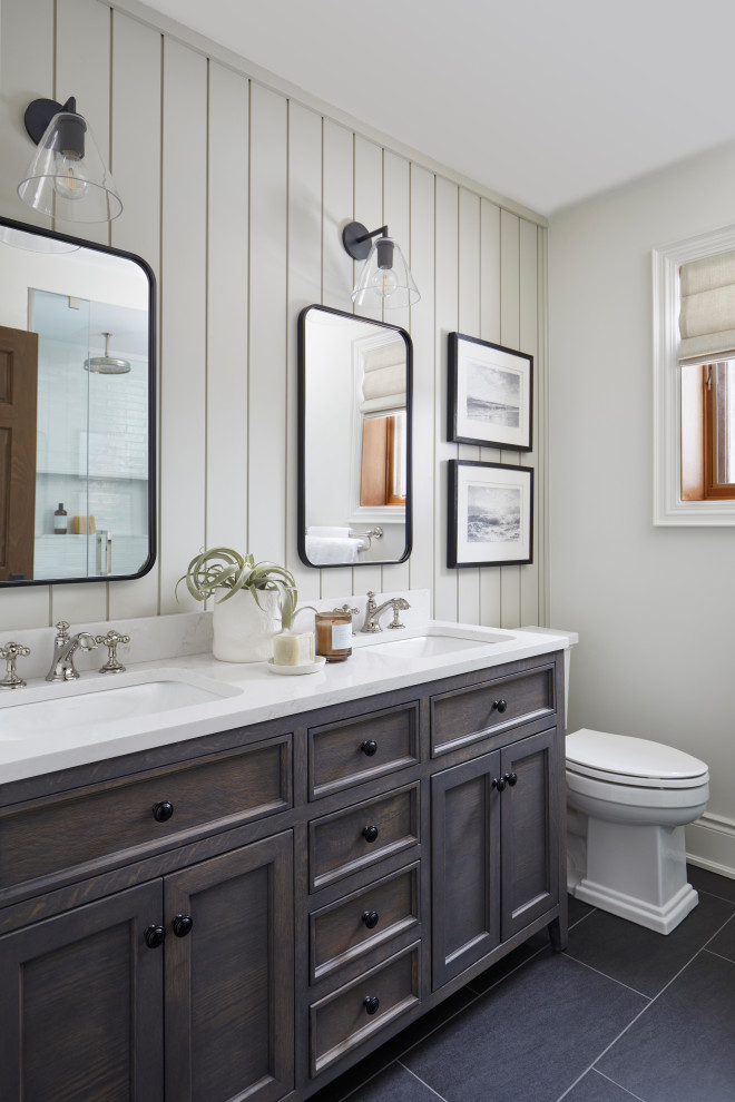 Alcove shower - small traditional 3/4 beige tile ceramic tile, gray floor and double-sink alcove shower idea with shaker cabinets, brown cabinets, a two-piece toilet, beige walls, an undermount sink, solid surface countertops, a hinged shower door, white countertops, a niche and a built-in vanity