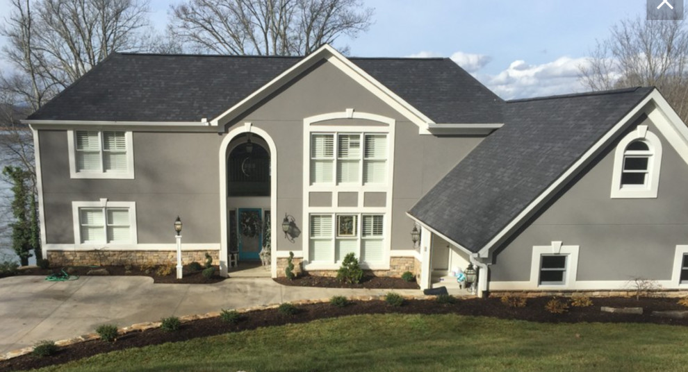 Photo of a transitional three-storey stucco grey house exterior in Other with a gable roof and a shingle roof.