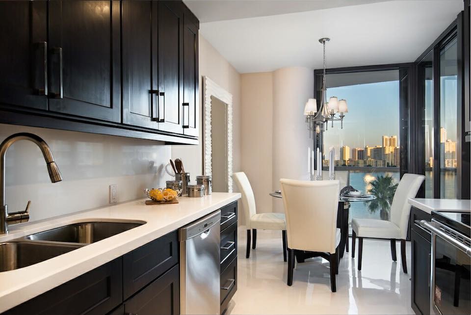 This is an example of a small contemporary galley separate kitchen in Miami with flat-panel cabinets, limestone benchtops, white splashback, limestone splashback, ceramic floors, multiple islands, white floor and white benchtop.