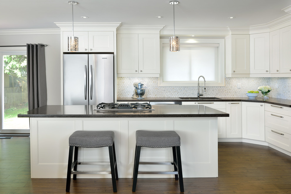 Transitional galley kitchen in Toronto with an undermount sink, beaded inset cabinets, white cabinets, multi-coloured splashback, stainless steel appliances, medium hardwood floors and with island.