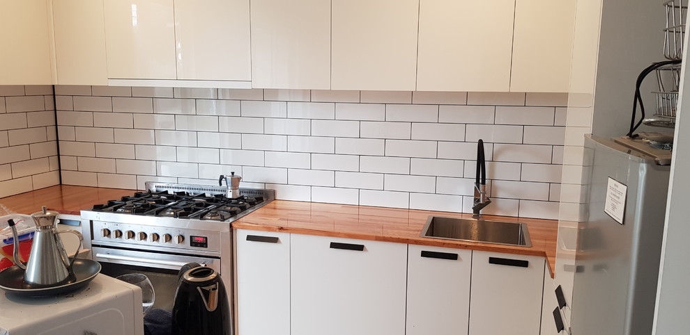 Design ideas for a small traditional u-shaped open plan kitchen in Melbourne with open cabinets, white cabinets, wood benchtops, white splashback, subway tile splashback, stainless steel appliances, medium hardwood floors, with island and an integrated sink.