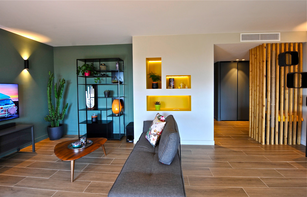 Exemple d'une grande salle de séjour tendance ouverte avec un mur vert, un sol en carrelage de céramique, un téléviseur fixé au mur, un sol beige et éclairage.