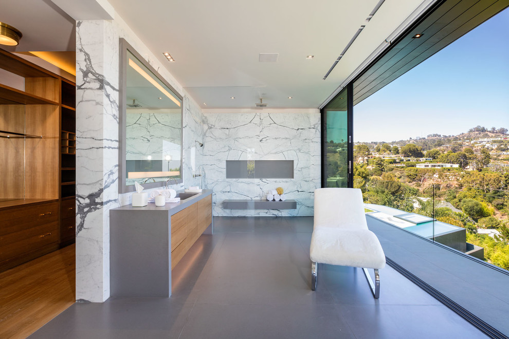 This is an example of a contemporary master bathroom in New York with flat-panel cabinets, light wood cabinets, white tile, grey floor and an open shower.