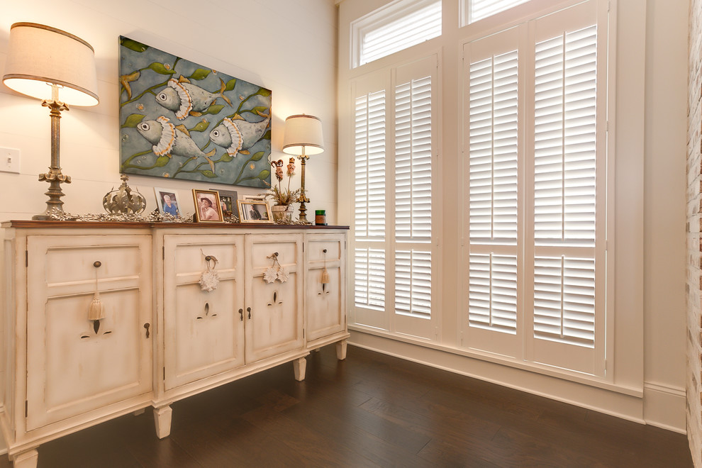 This is an example of a mid-sized beach style separate dining room in New Orleans with white walls, dark hardwood floors and brown floor.