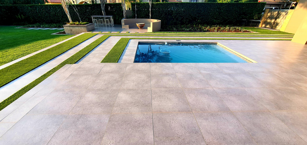 Cette photo montre un grand piscine avec aménagement paysager arrière moderne rectangle avec du carrelage.