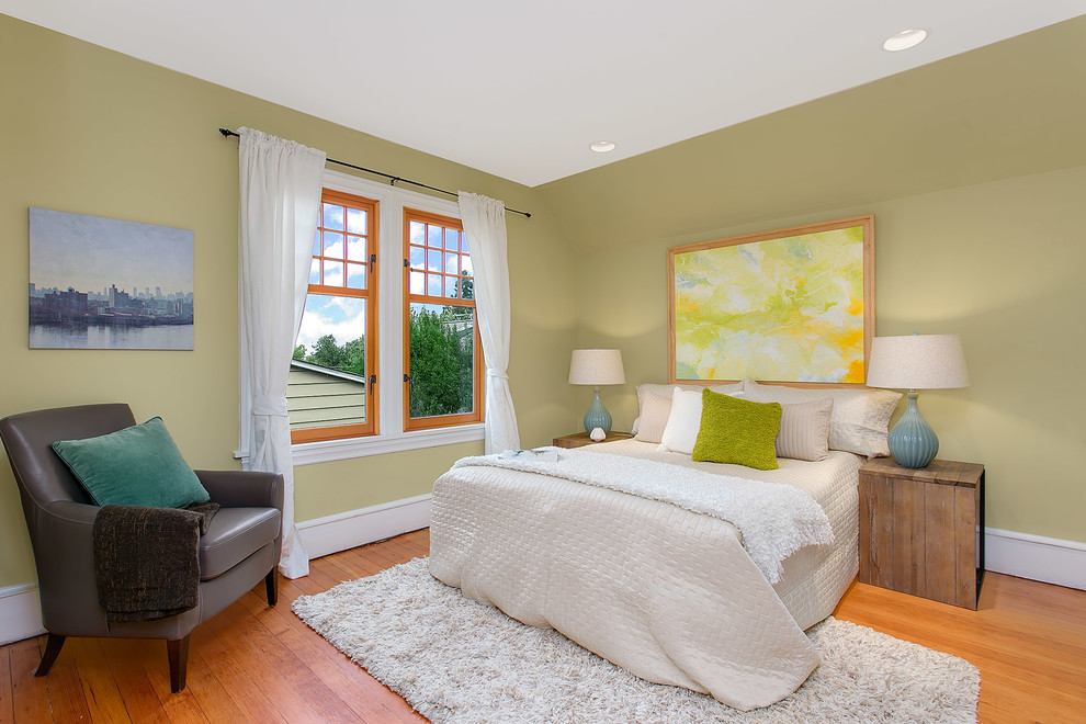 This is an example of a large modern guest bedroom in Seattle with yellow walls and light hardwood floors.