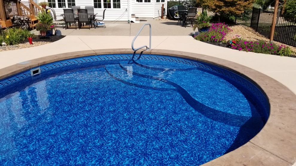 Large traditional backyard custom-shaped pool in St Louis with stamped concrete.