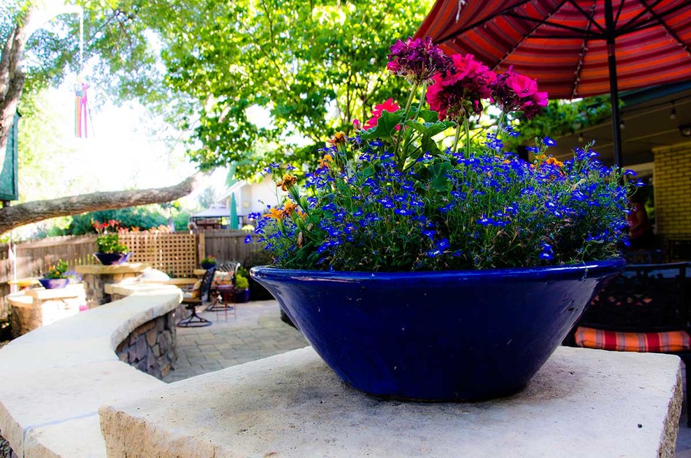 This is an example of a traditional backyard garden for summer in Denver with a container garden and natural stone pavers.