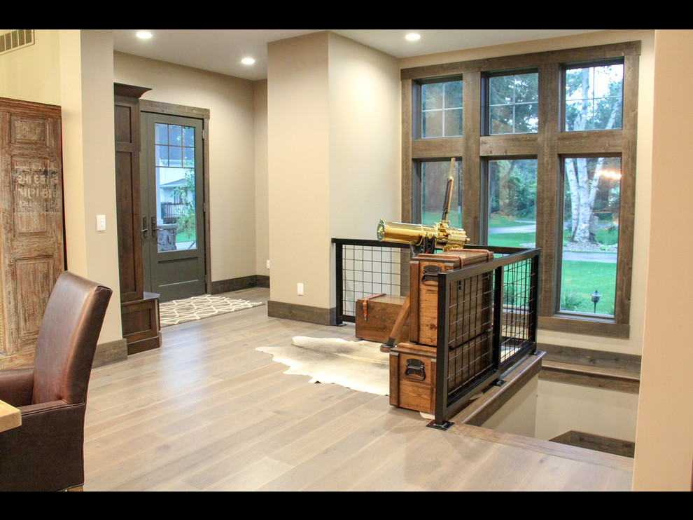 Mountain style medium tone wood floor and brown floor front door photo with beige walls and a gray front door