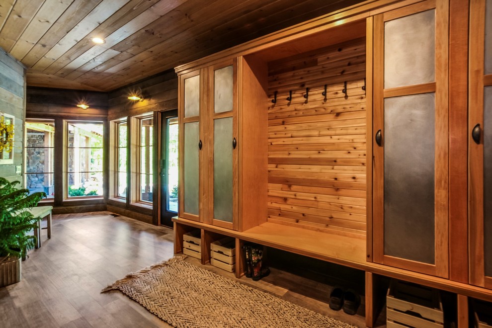 This is an example of a mid-sized country mudroom in Grand Rapids with brown walls, vinyl floors, a single front door, a glass front door and brown floor.