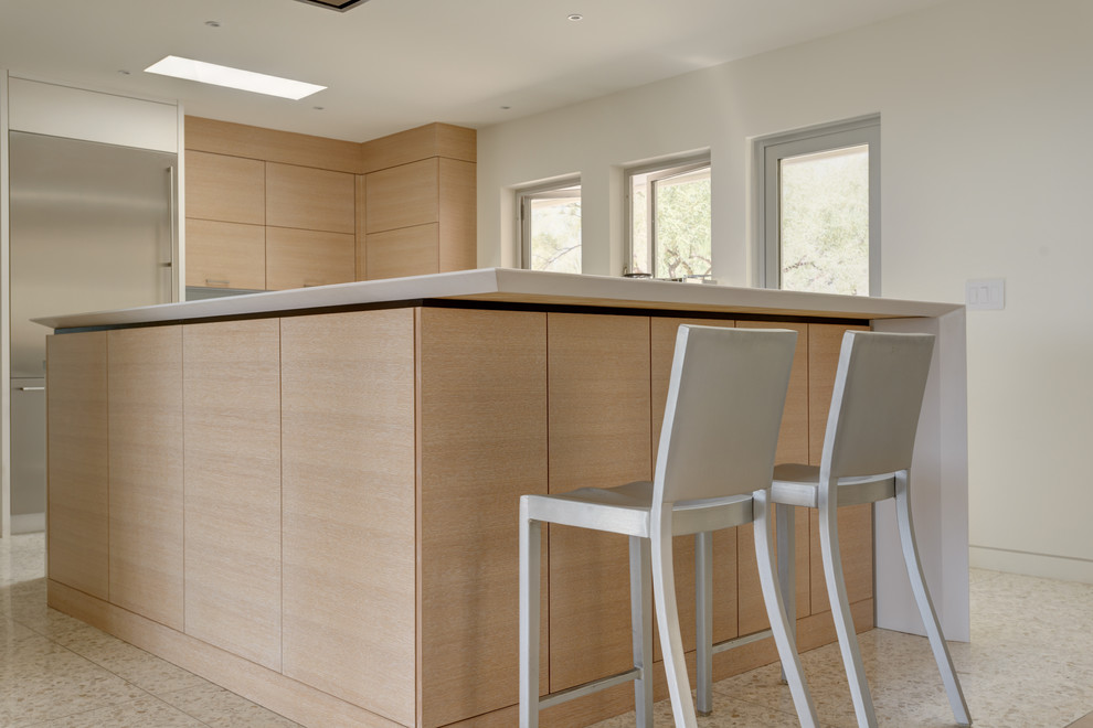This is an example of a mid-sized midcentury l-shaped eat-in kitchen in Phoenix with an undermount sink, flat-panel cabinets, light wood cabinets, quartz benchtops, blue splashback, glass tile splashback, stainless steel appliances, concrete floors and with island.