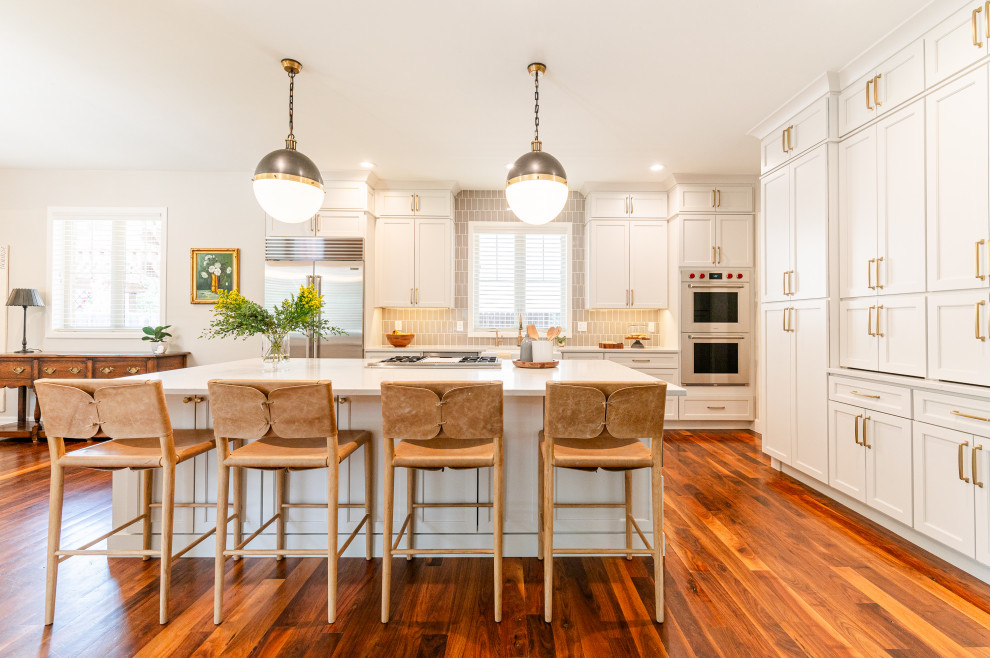 Open concept kitchen - large transitional l-shaped dark wood floor and brown floor open concept kitchen idea in Denver with a farmhouse sink, shaker cabinets, beige cabinets, quartz countertops, beige backsplash, ceramic backsplash, stainless steel appliances, an island and white countertops