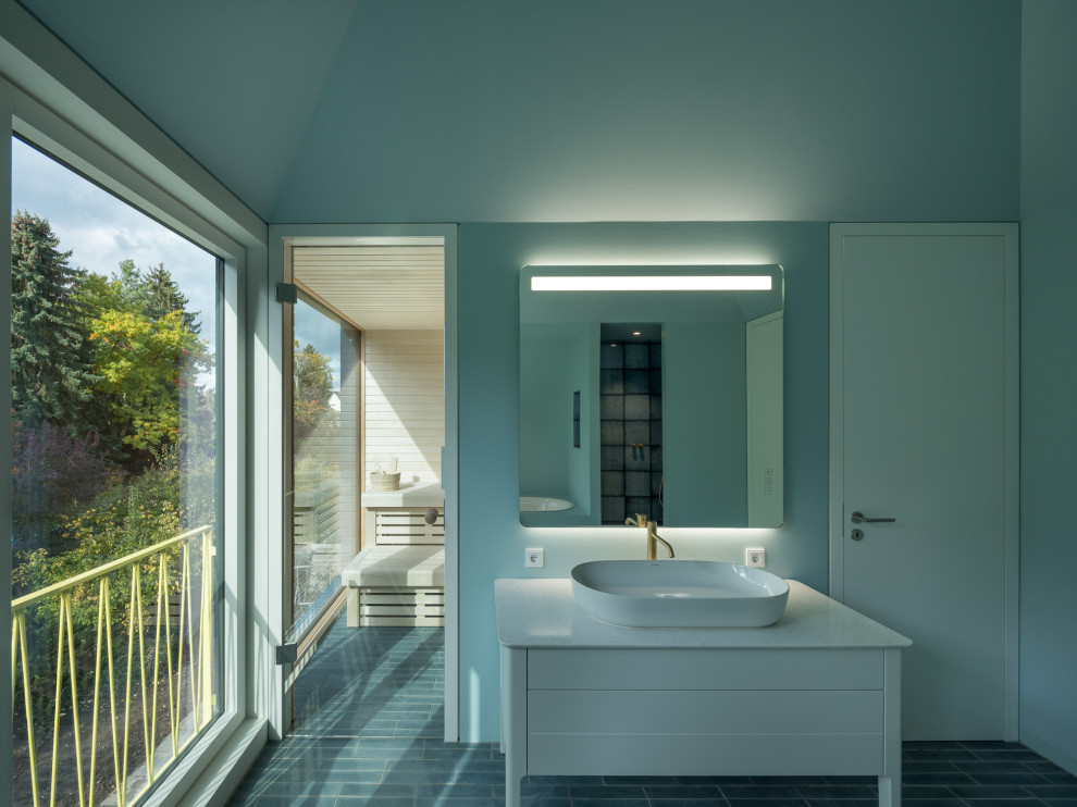 This is an example of a mid-sized contemporary master bathroom in Berlin with white cabinets, a wall-mount toilet, cement tiles, a vessel sink, engineered quartz benchtops, blue floor, white benchtops, an enclosed toilet, a single vanity and a freestanding vanity.