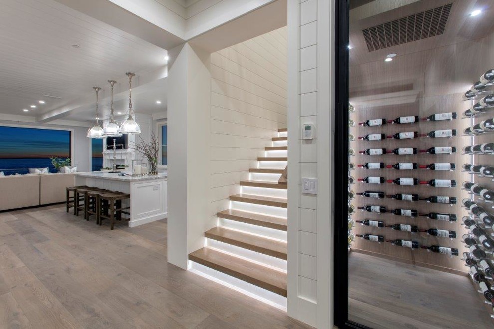 Mid-sized beach style wine cellar in Orange County with light hardwood floors, display racks and brown floor.