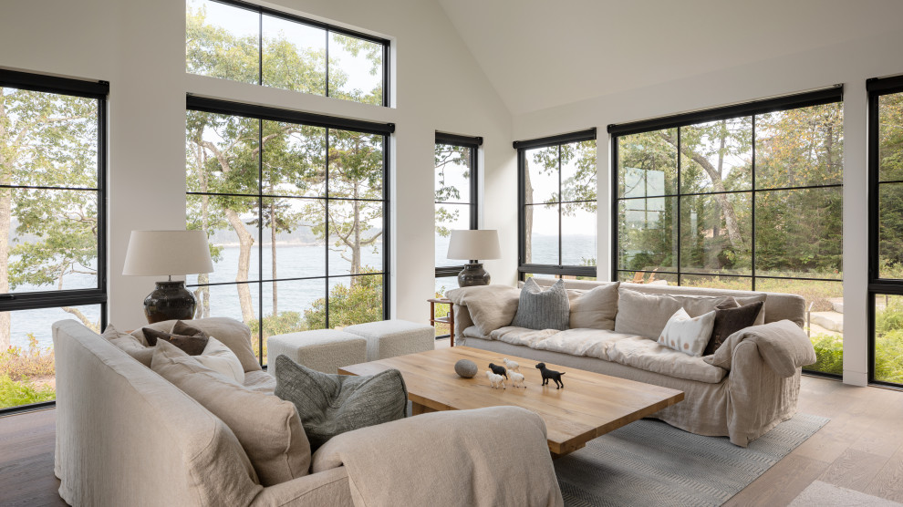 Example of a beach style medium tone wood floor, brown floor and vaulted ceiling living room design in Portland Maine with white walls