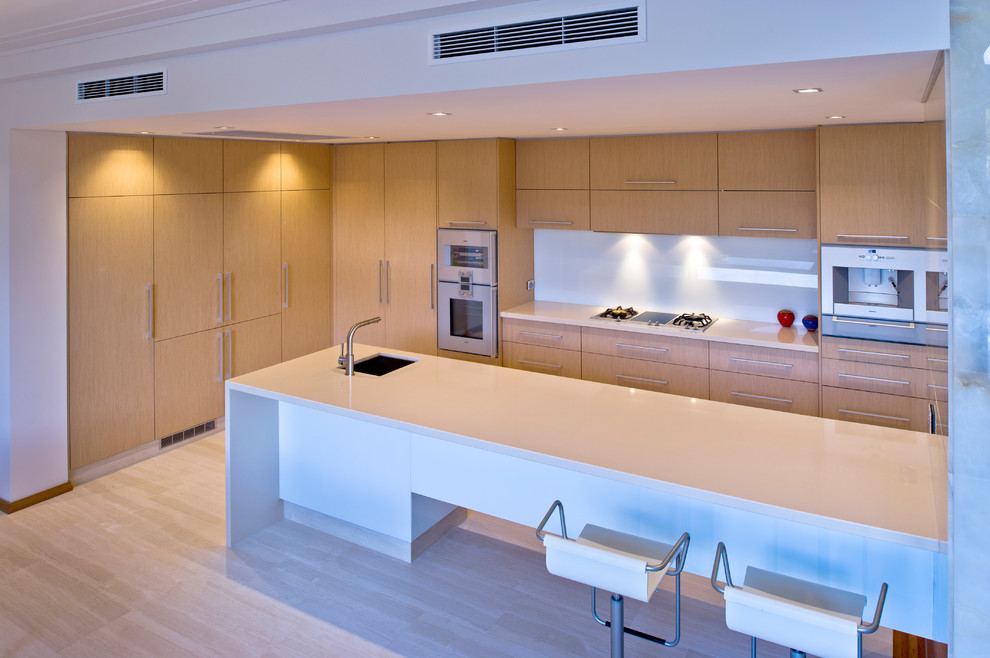 Photo of a large contemporary eat-in kitchen in Perth with an undermount sink, flat-panel cabinets, light wood cabinets, quartz benchtops, metallic splashback, glass sheet splashback, stainless steel appliances, a peninsula and light hardwood floors.