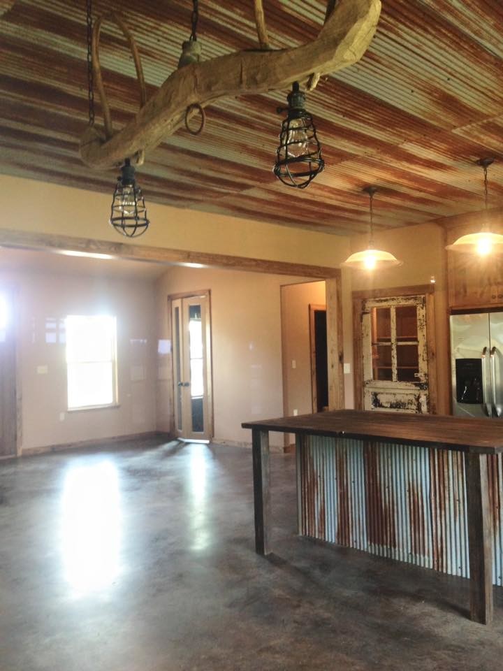 Mountain style concrete floor eat-in kitchen photo with an undermount sink, flat-panel cabinets, medium tone wood cabinets, granite countertops, beige backsplash, stone tile backsplash, stainless steel appliances and an island