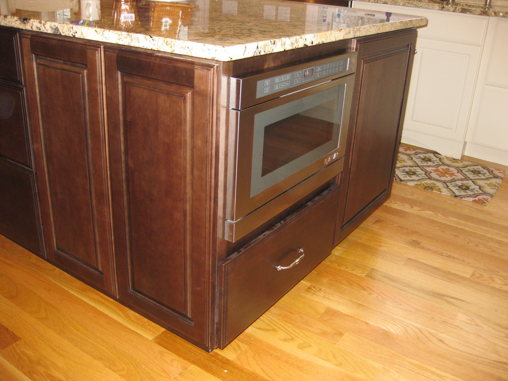 Eat-in kitchen - transitional l-shaped light wood floor eat-in kitchen idea in Boston with raised-panel cabinets, granite countertops, stainless steel appliances, an undermount sink, white cabinets, beige backsplash, ceramic backsplash and an island