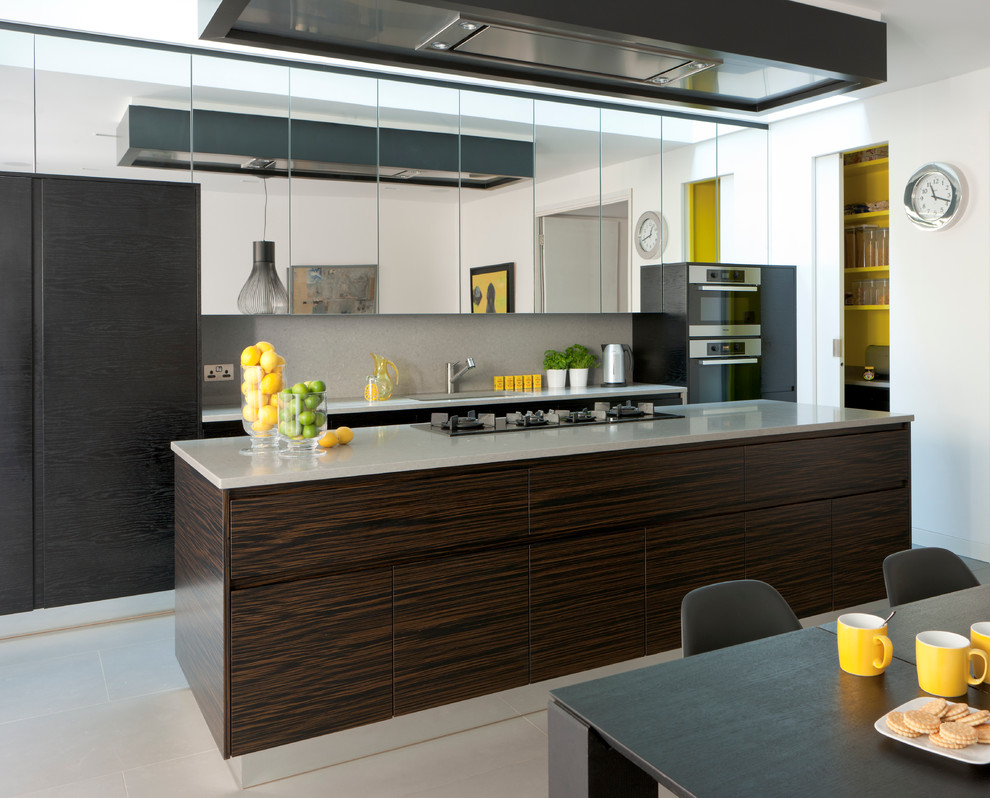 Photo of a contemporary galley eat-in kitchen in London with an undermount sink, flat-panel cabinets, black cabinets, grey splashback and stainless steel appliances.