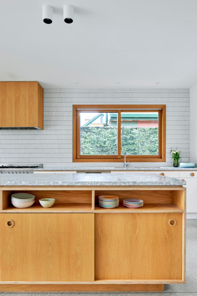 Medium sized midcentury galley kitchen in Melbourne with a single-bowl sink, flat-panel cabinets, light wood cabinets, terrazzo worktops, white splashback, mosaic tiled splashback, stainless steel appliances, concrete flooring, an island, grey floors and grey worktops.