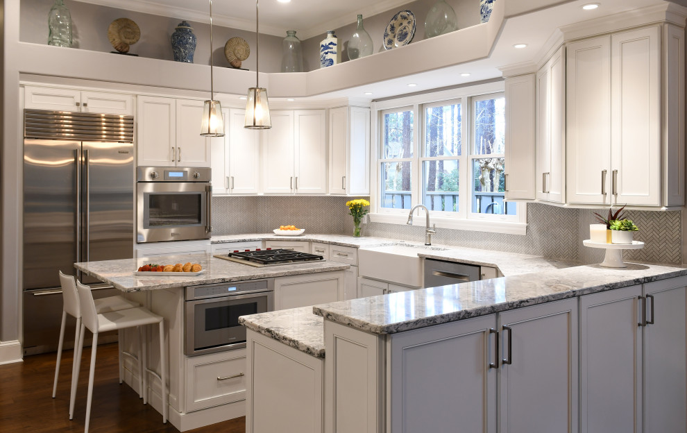 Design ideas for a large traditional u-shaped eat-in kitchen in Atlanta with a farmhouse sink, flat-panel cabinets, white cabinets, solid surface benchtops, grey splashback, porcelain splashback, stainless steel appliances, with island, brown floor and multi-coloured benchtop.