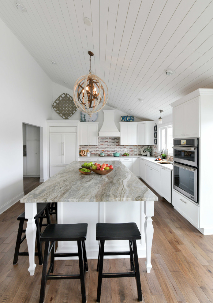 Inspiration for a large transitional u-shaped eat-in kitchen in Columbus with an undermount sink, recessed-panel cabinets, white cabinets, granite benchtops, grey splashback, brick splashback, panelled appliances, medium hardwood floors, with island, brown floor and grey benchtop.