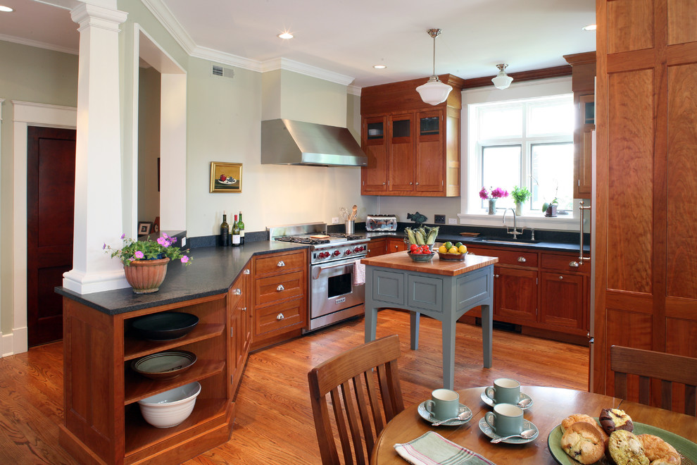 Mid-sized arts and crafts u-shaped eat-in kitchen in DC Metro with shaker cabinets, medium wood cabinets, black splashback, panelled appliances, a double-bowl sink, soapstone benchtops, light hardwood floors, with island and red floor.